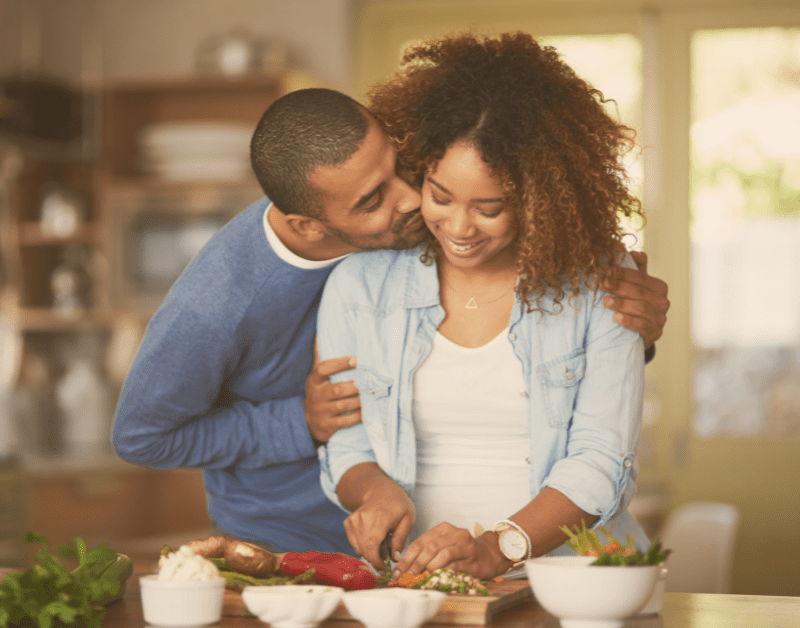 man kissing woman in the kitchen both smiling