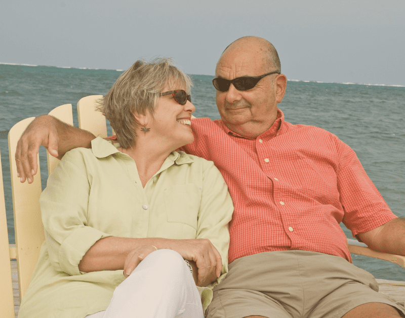older couple sitting on beach together smiling