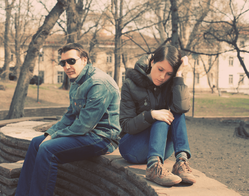 man and woman sitting outside separately