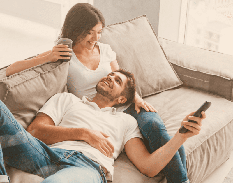 man and woman sitting on couch smiling at each other