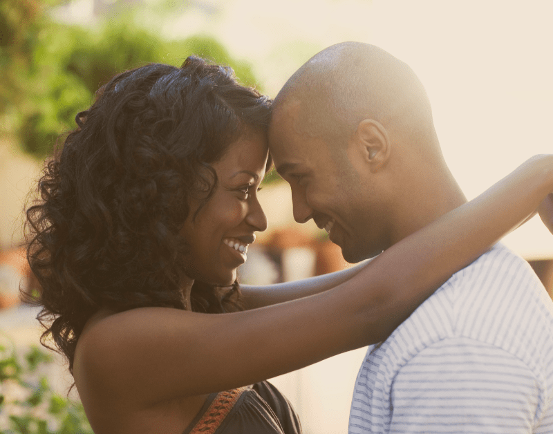 black man and woman standing outside hugging and looking at each other and smiling