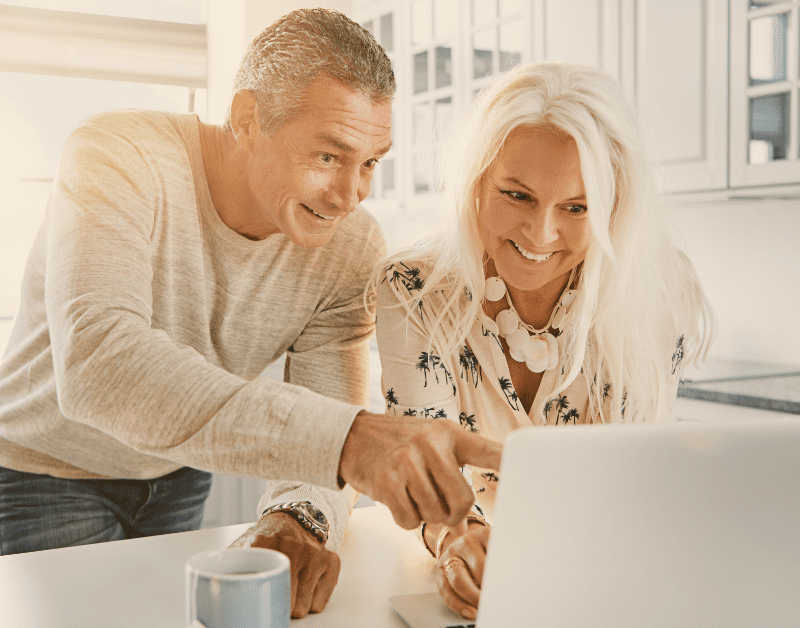 man and woman looking at laptop and smiling