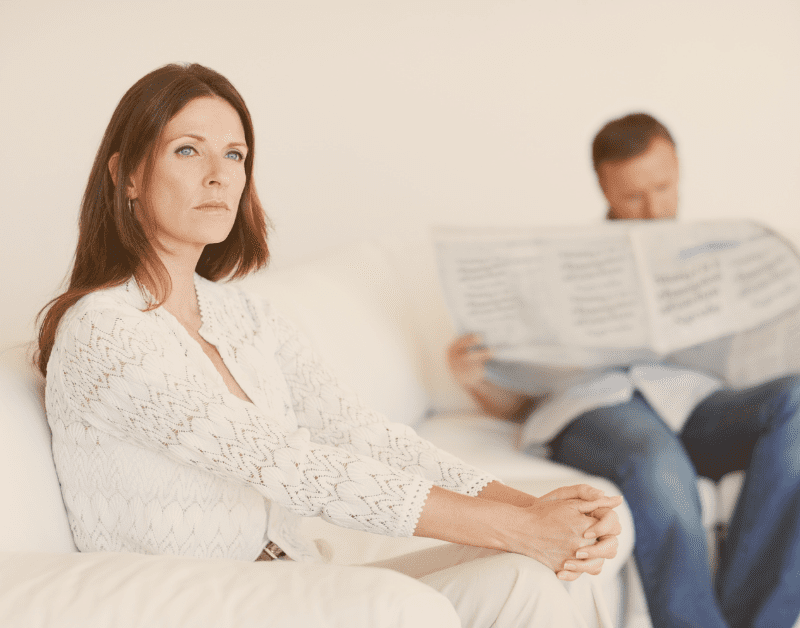 woman sitting on couch with man in the background