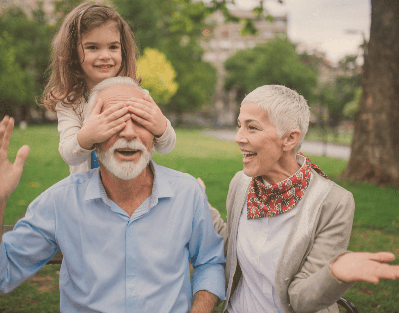 older man and woman outside smiling with little girl