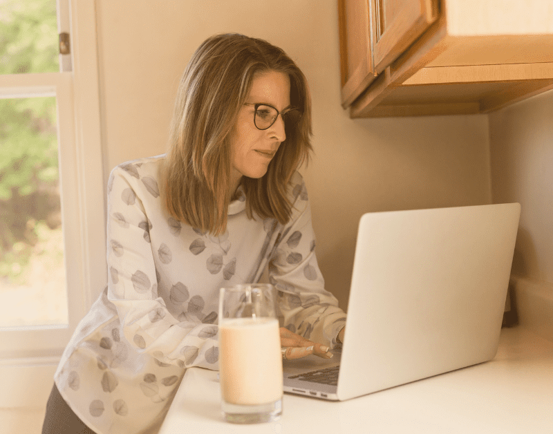 middle aged woman on laptop at kitchen counter