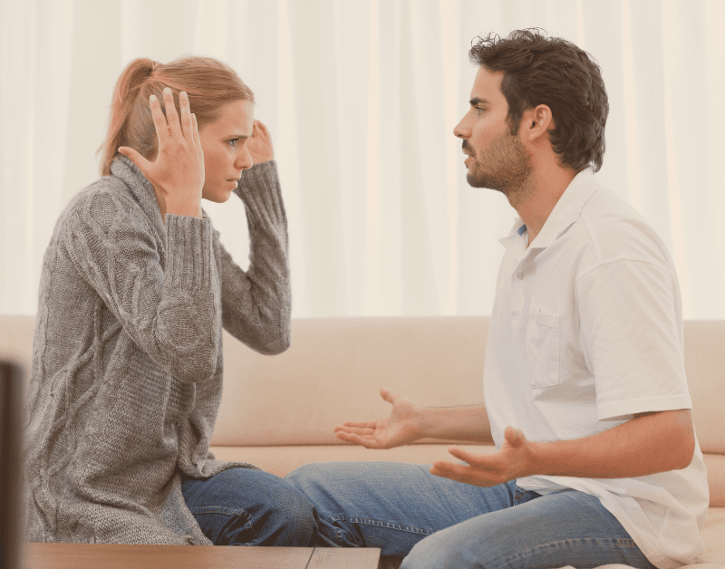 couple sitting on couch facing each other arguing