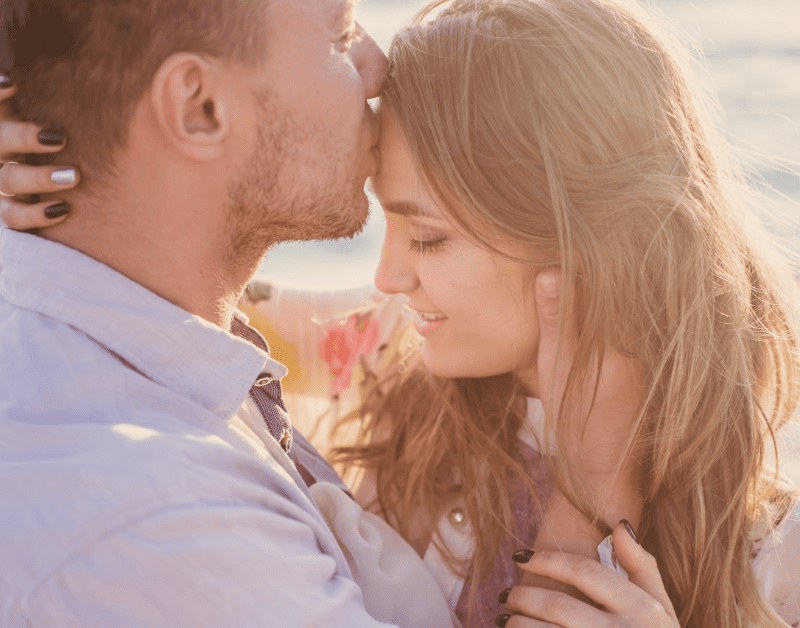 man and woman outside with man kissing womans forehead
